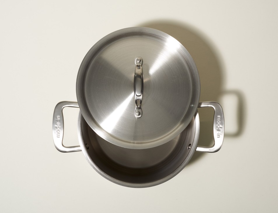 Stainless steel cooking pan with lid and handles viewed from above.