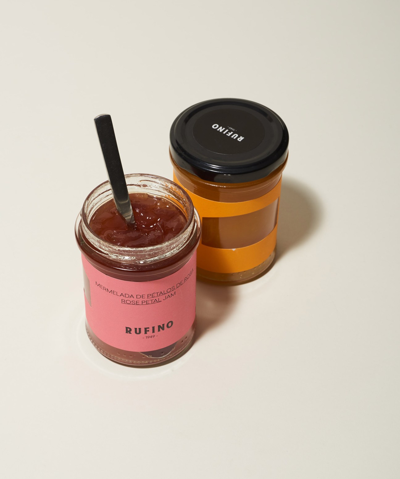 Two jars of Rufino jam – rose petal and mango varieties – with black lids against a neutral background.