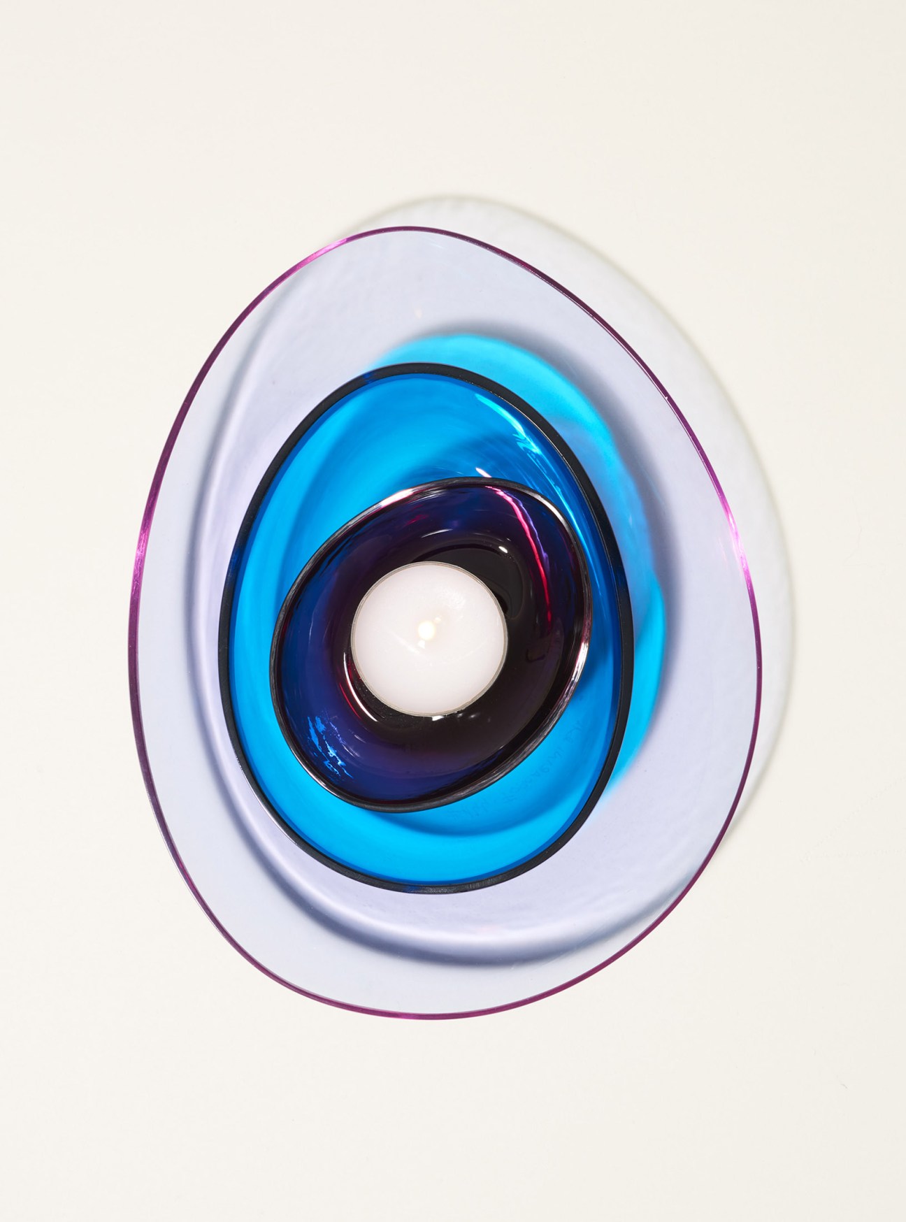 Foscarini glass candleholder with nested oval bowls in white, blue and dark blue containing a small tea light.