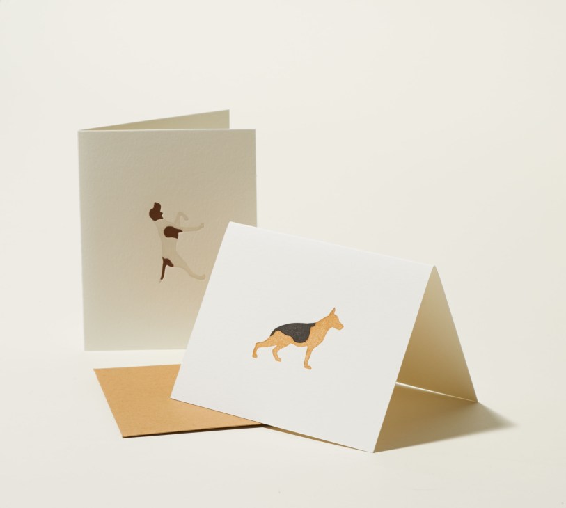 Illustration of greeting cards featuring dog breed designs printed on cardstock in cream and gold tones.