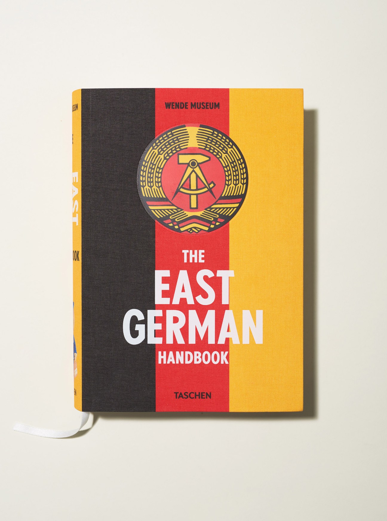 The East German Handbook book cover by Wende Museum and Taschen featuring East German flag colors and state emblem.