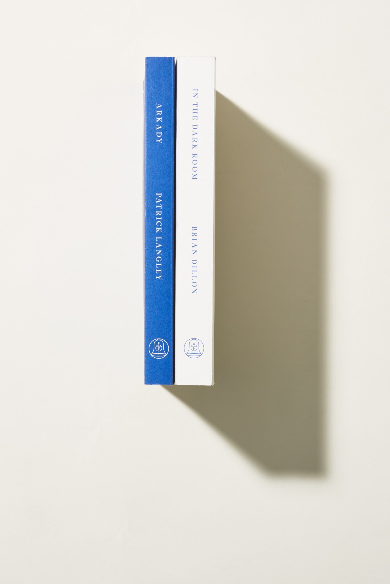 Two books stacked together: a blue-spined copy of 'Arkady' by Brian Dillon and a white-spined copy of 'In the Dark Room' by Fitzcarraldo Editions.