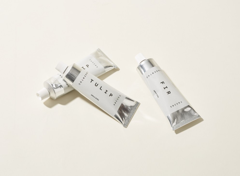 Tangent GC hand cream tubes in white and metallic packaging on neutral background.