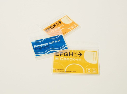 Three colorful zip-lock bags with airport-inspired graphics in yellow, blue, and orange by Midori.