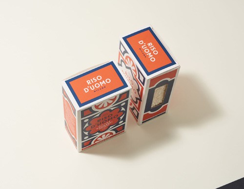 Two boxes of Riso D'uomo risotto rice with orange labels and decorative patterned packaging.