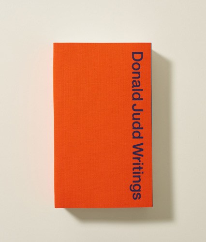 Donald Judd Writings book with orange cover and blue typography.