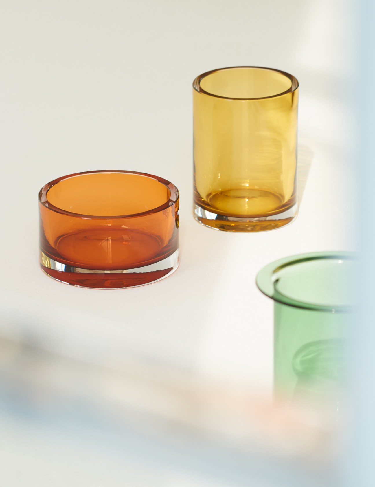 Three hand-blown glass vases in orange, yellow, and green with metallic rims.
