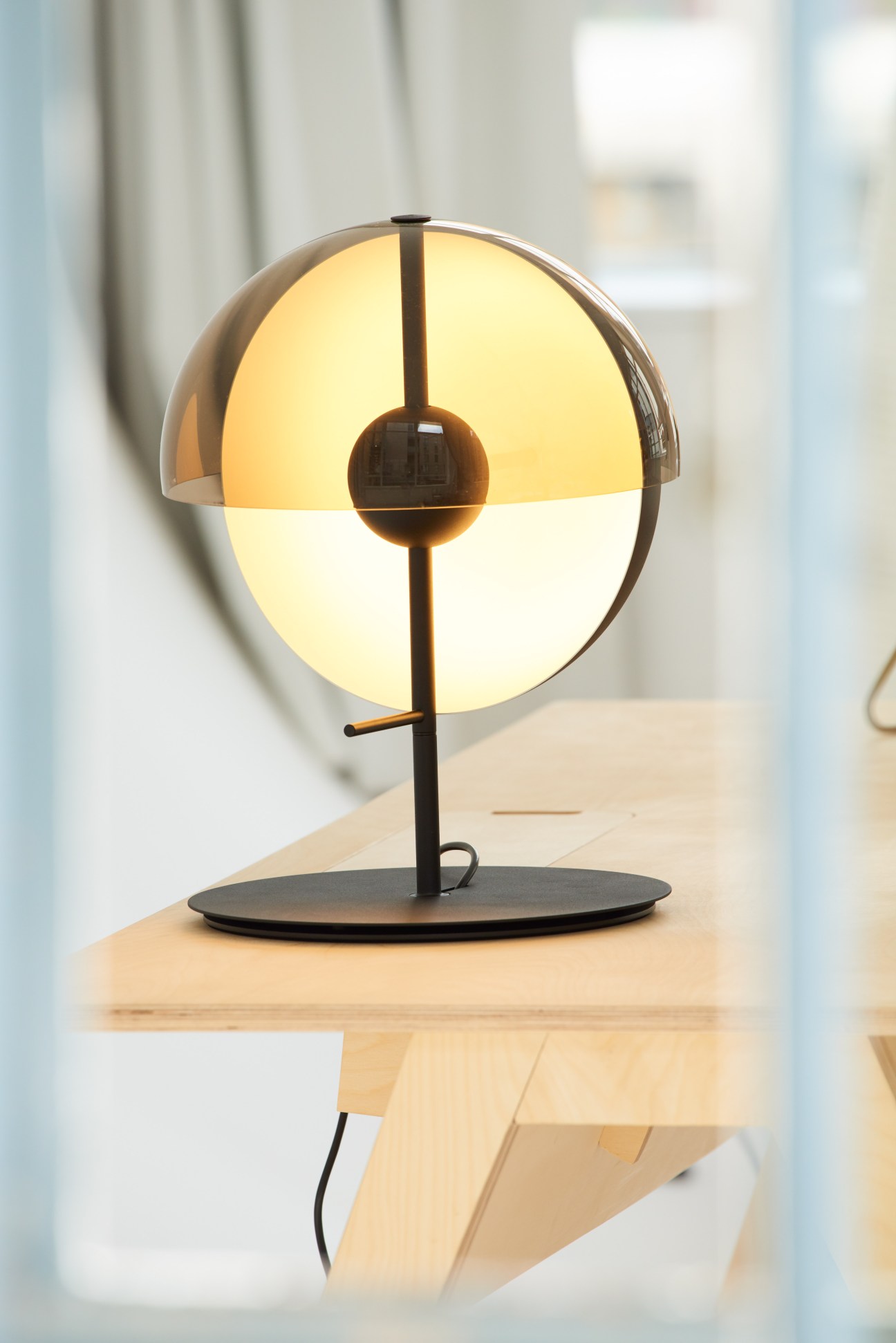 Theia lamp by Marset with illuminated intersecting half-spheres on black base.