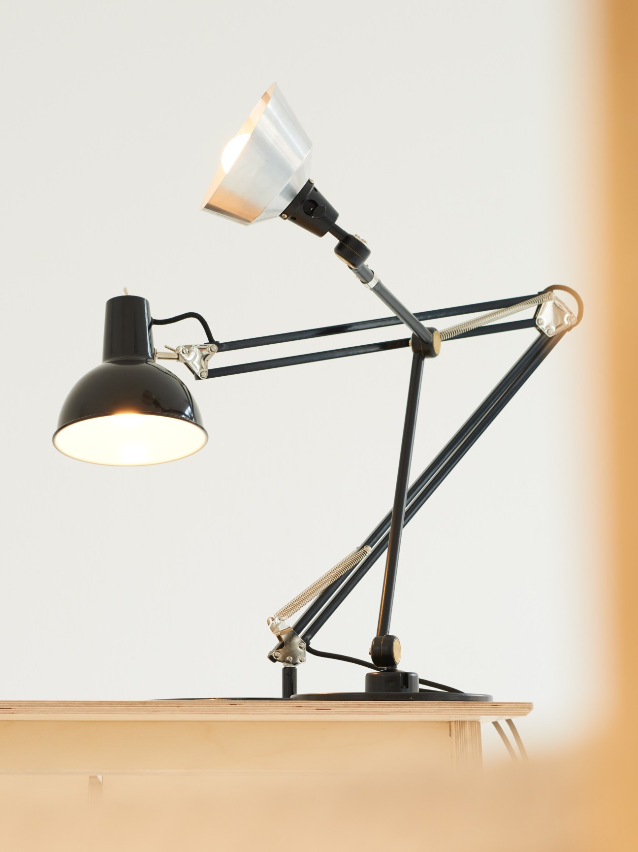 Midgard Federzugleuchte springloaded lamp with black retro shade and articulated arms on wooden surface.