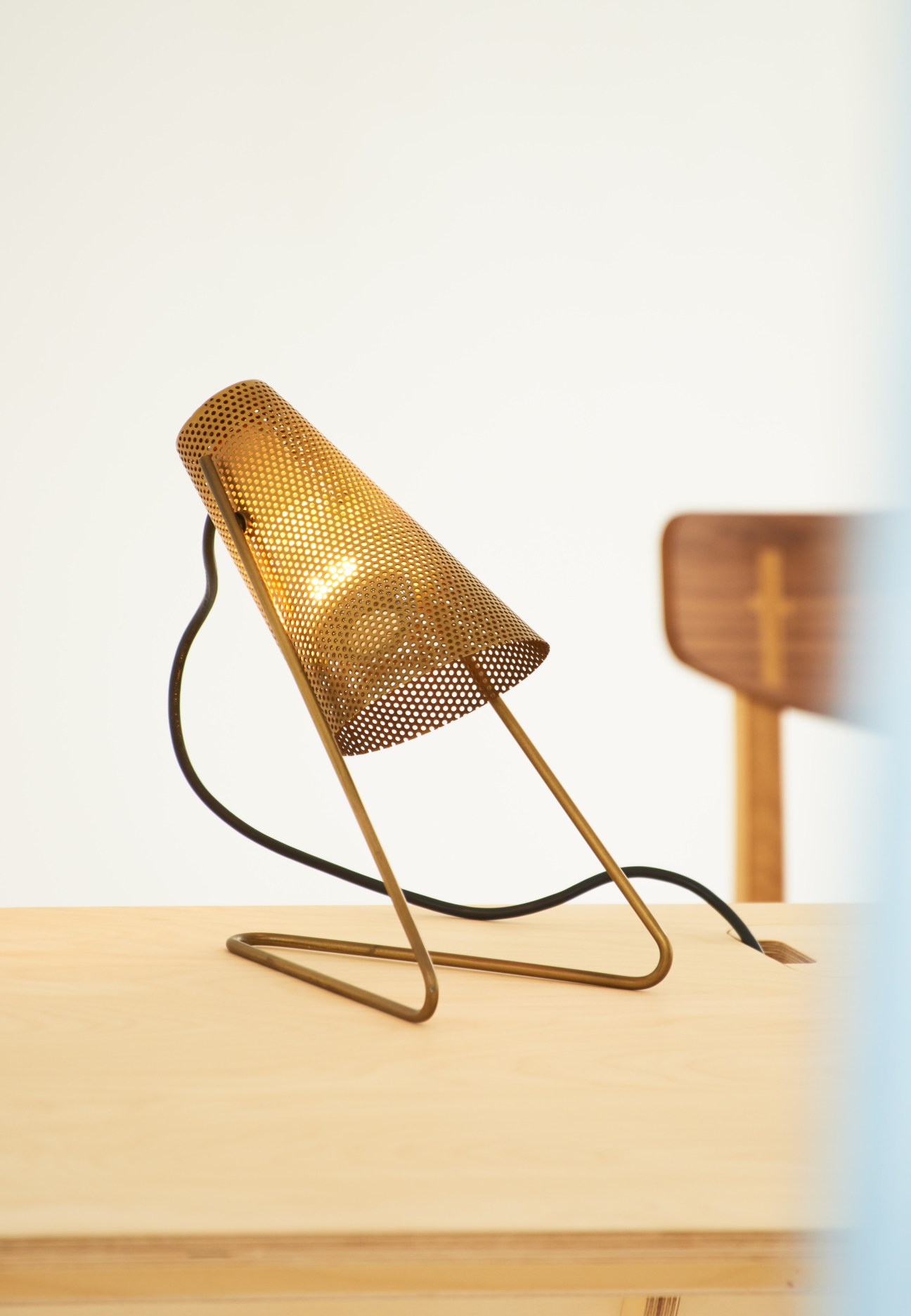 Midgard Federzugleuchte springloaded lamp with perforated brass shade and black cord on wooden surface.