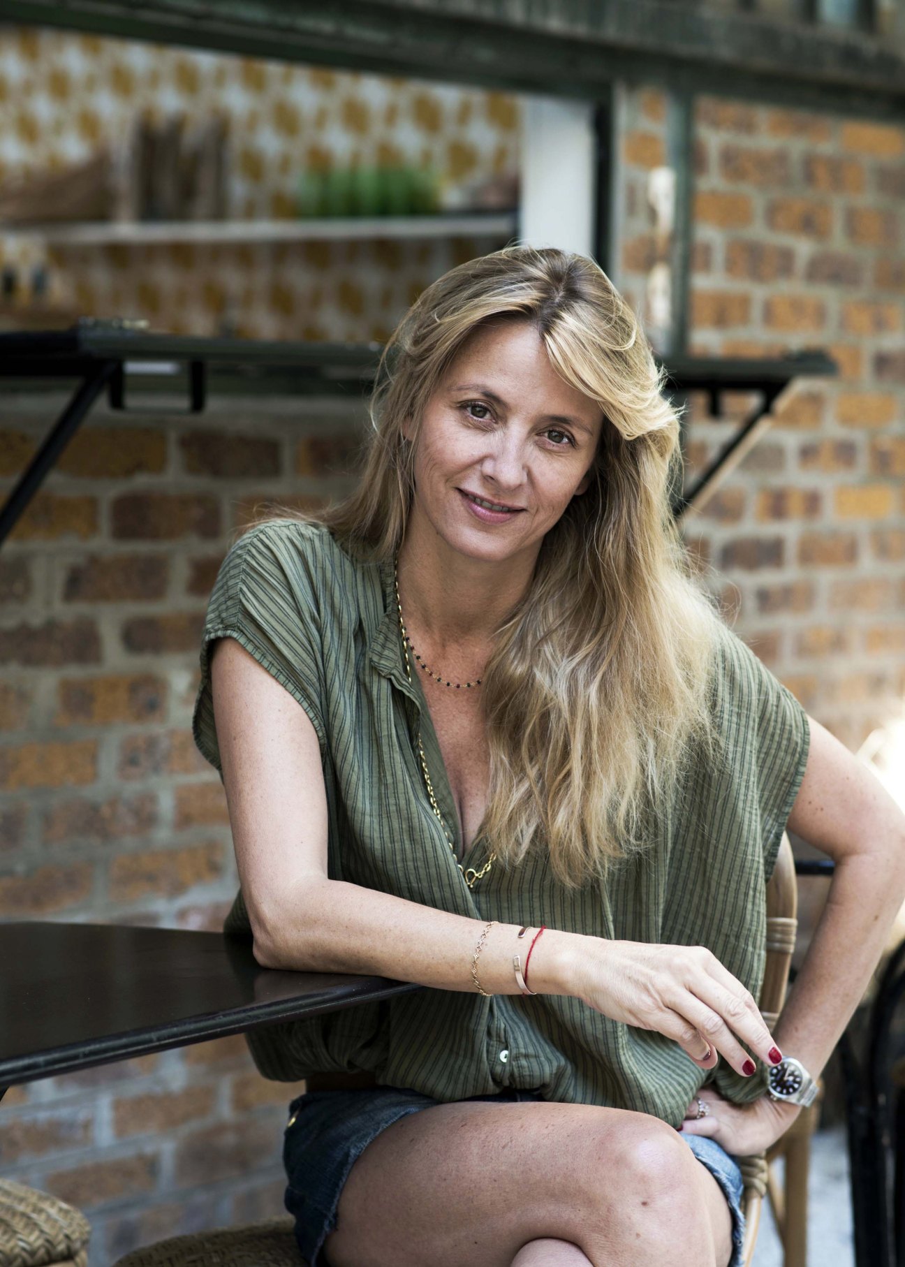 Interior designer Sarah Lavoine smiling at her Paris showroom with exposed brick walls