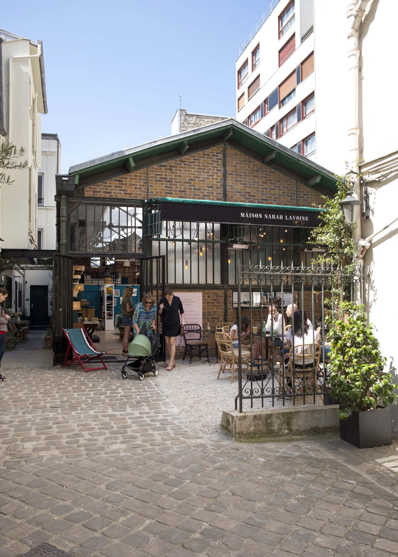 Exterior storefront of Maison Sarah Lavoine in the Passy neighborhood with brick building, black metal doors and signage
