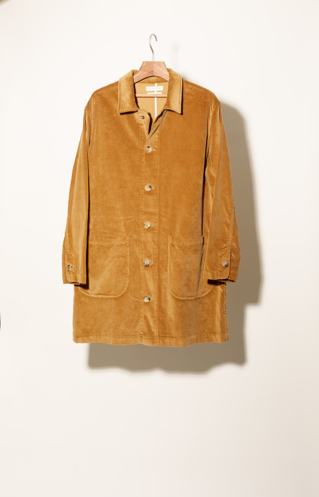 Kestin Hare corduroy coat in brown displayed on a wooden hanger