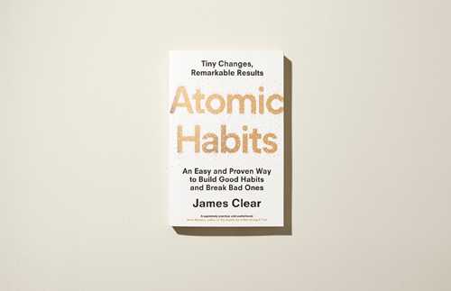 Book cover of Atomic Habits by James Clear showing title in large peach text on white background.