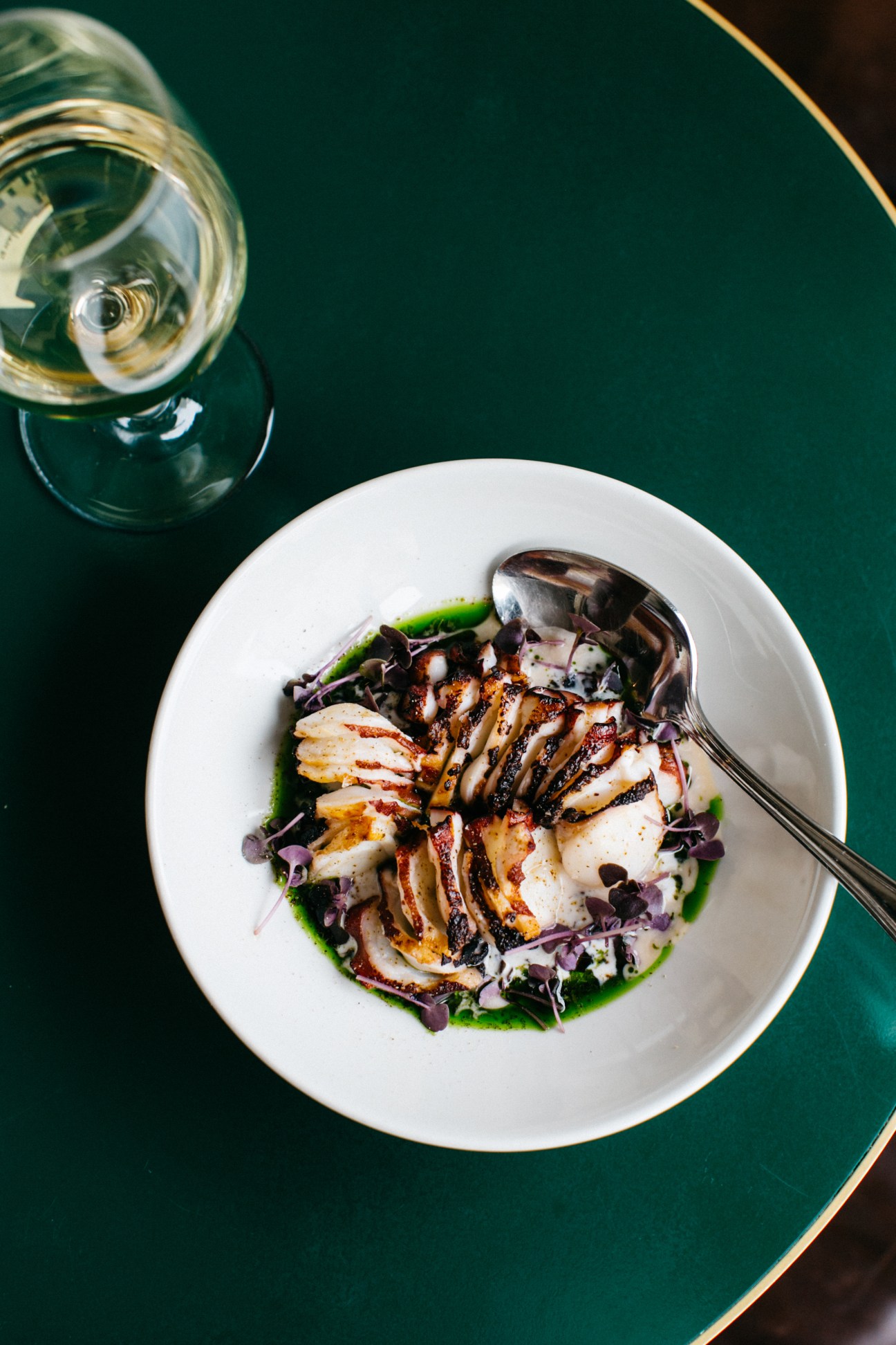 Octopus dish at 10 William Street restaurant in Sydney with wine glass on green table.