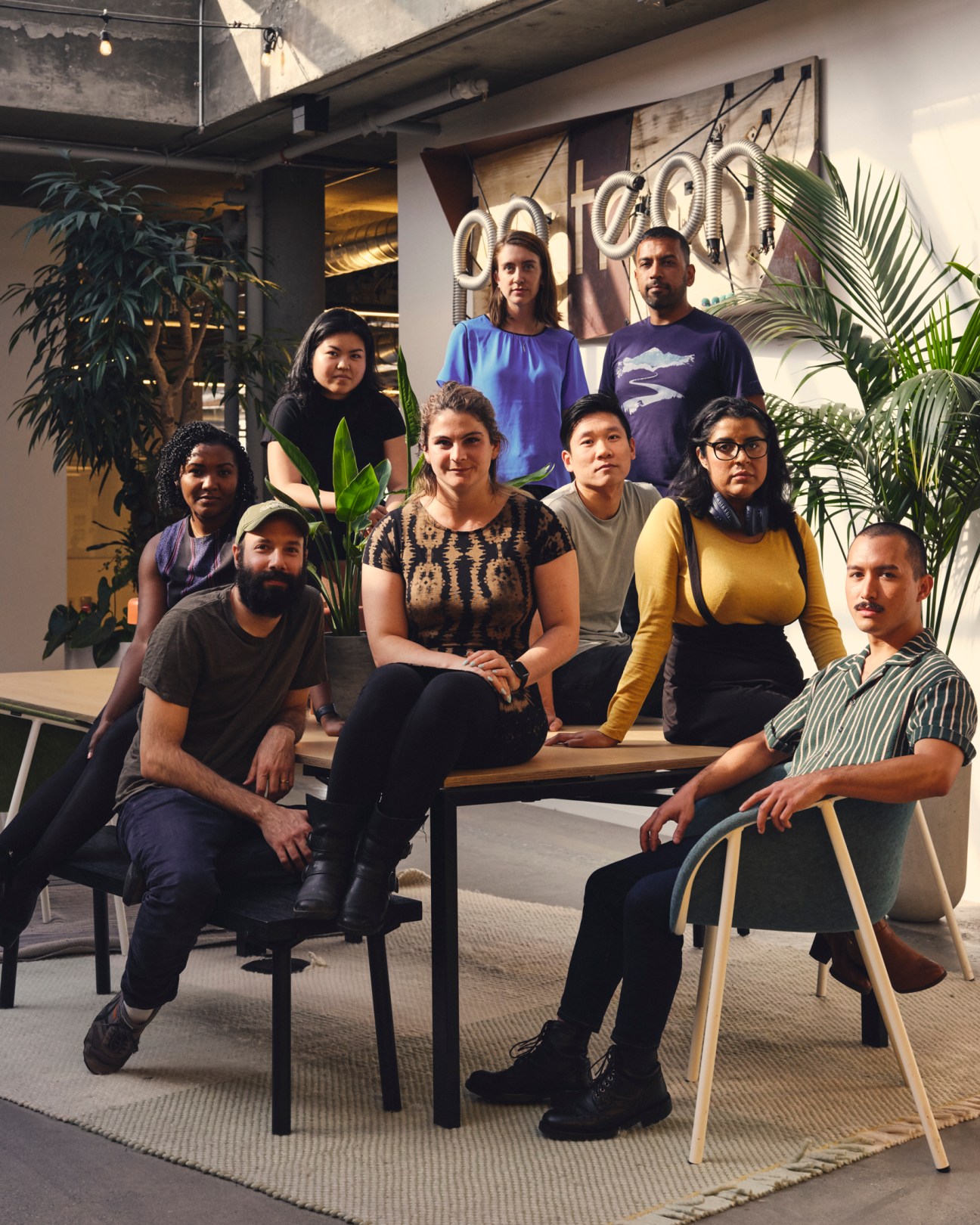 Jack Conte, CEO of Patreon, seated on left with team members in modern office space with neon signage and plants.