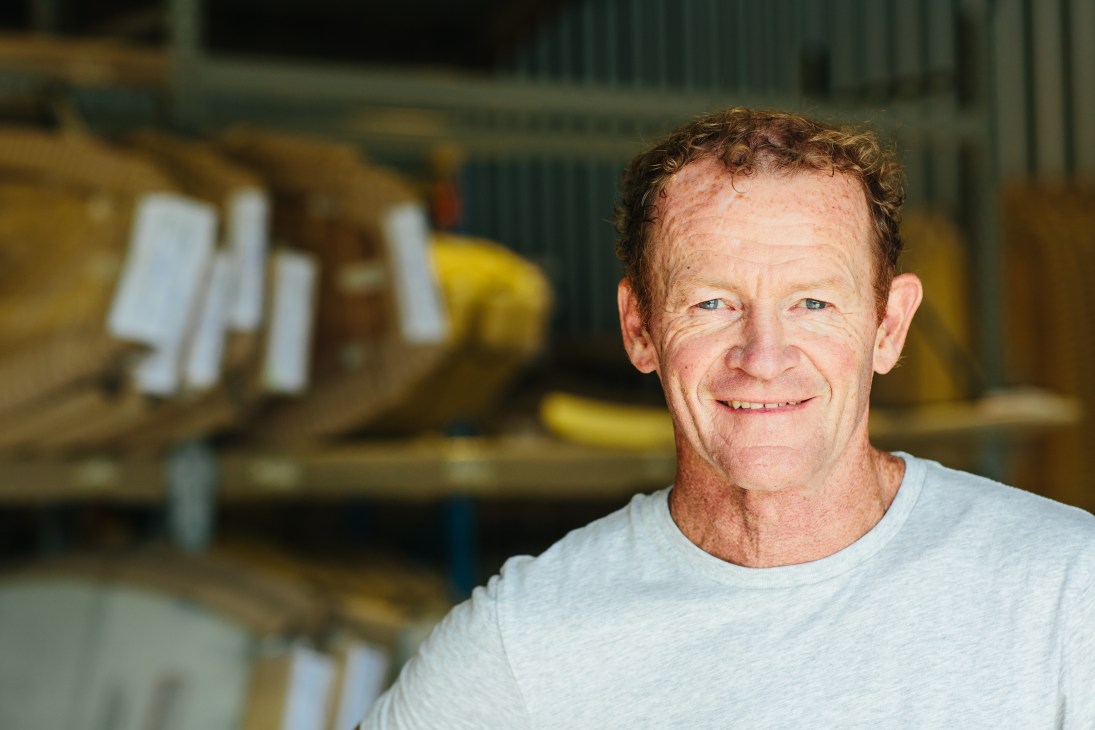 Portrait of Nev Hyman, founder of Firewire Surfboards and NevHouse, smiling in front of a workshop.