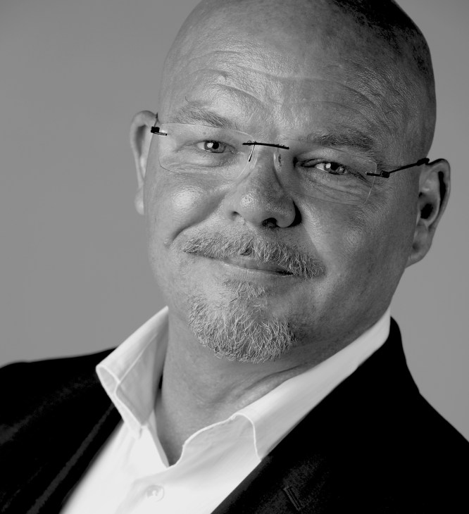 Portrait of Barry Lee, architect and design director at DBI, wearing glasses and formal attire.