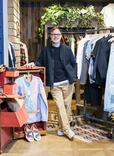 Bruce Pask, menswear director at Bergdorf Goodman, stands in his curated B Store shop displaying clothing and accessories.