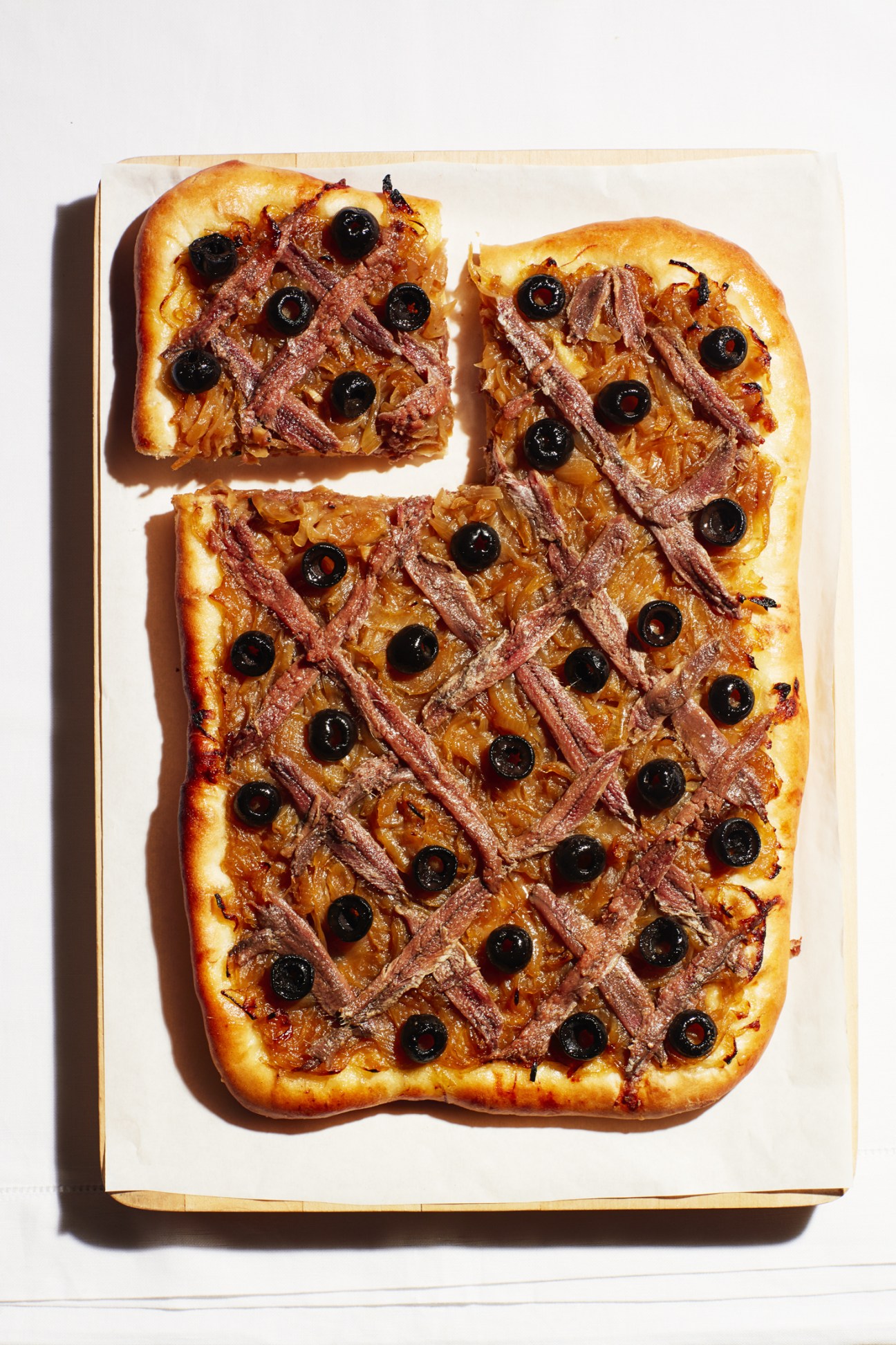 Pissaladière with caramelized onions, anchovy fillets in crisscross pattern and black olives.