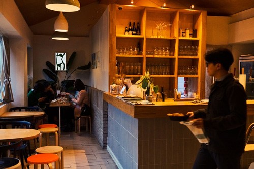 Interior of Strukt café with shelves of books, warm lighting, and customers seated at tables.