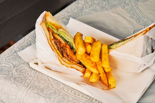 Bulgogi sandwich with barbecue sauce and golden fries served on white paper at Aussie restaurant.