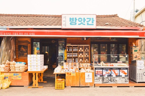Exterior of 1913 Songjeong Station Market with traditional storefront displaying soju bottles and dried goods.