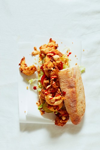 Prawn po' boy sandwich with fried shrimp, lettuce, tomato and pickles on a baguette.