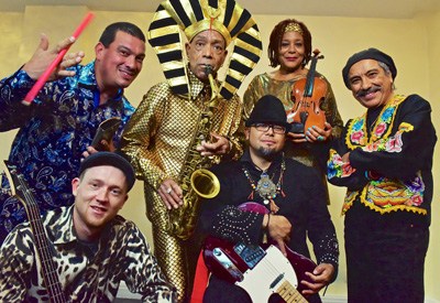 Idris Ackamoor & the Pyramids band members pose together in colorful, eclectic outfits and accessories.