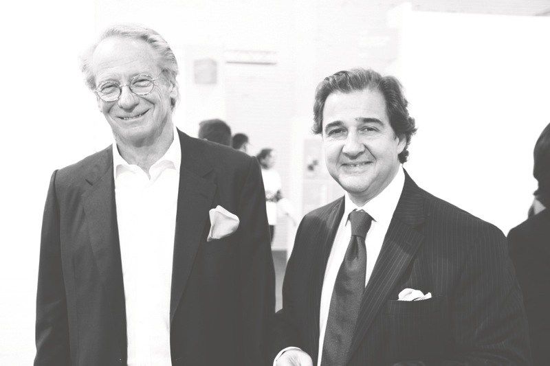 Two men in formal business attire at what appears to be an art event or gallery opening.
