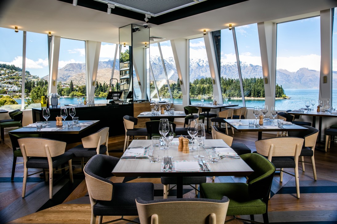 Modern restaurant interior with mountain views through floor-to-ceiling windows at QT Queenstown hotel.