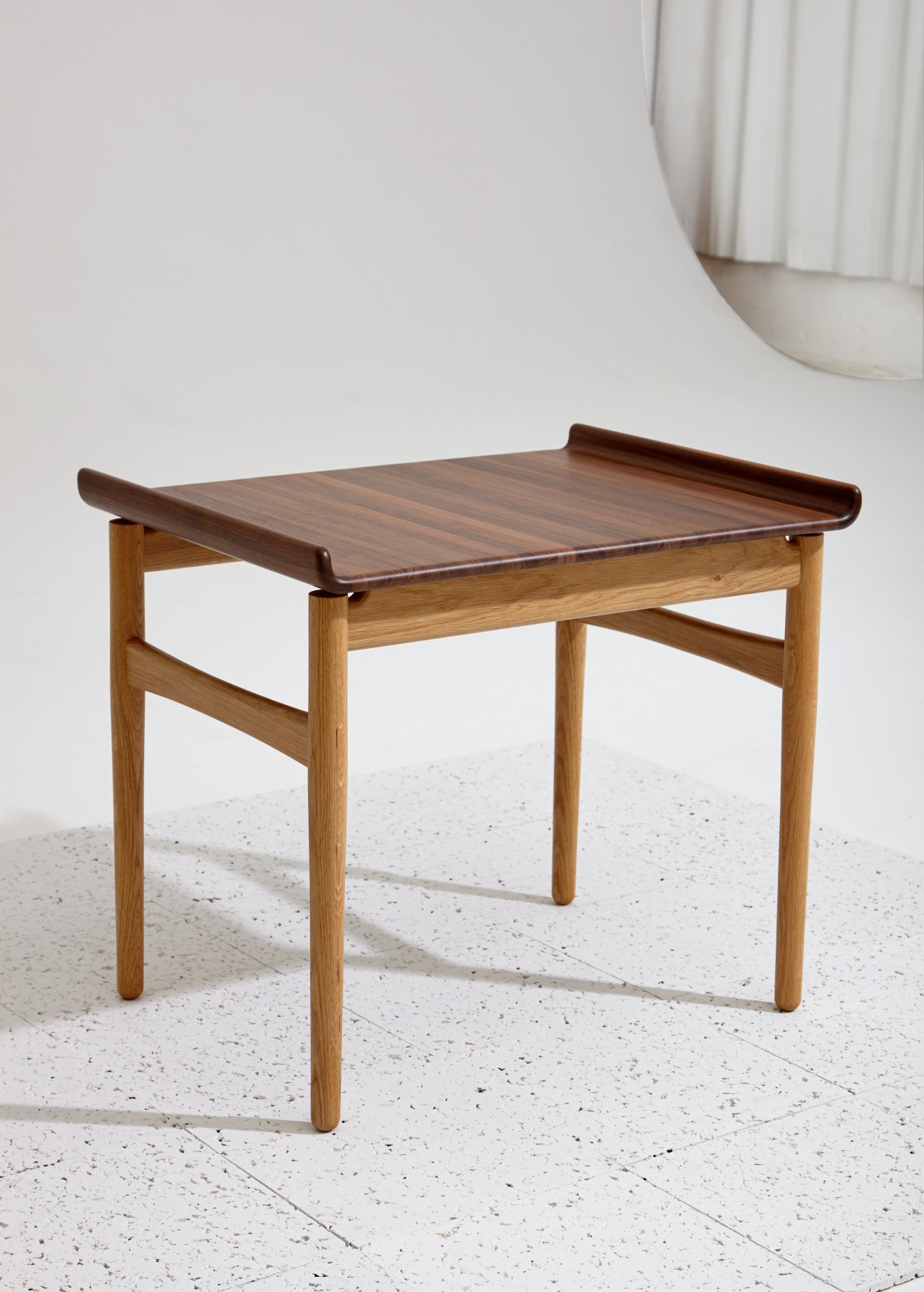 Hans J Wegner coffee table with curved walnut top and wooden legs on white floor.
