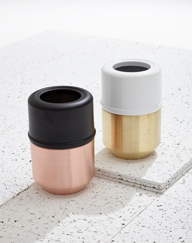 Two cylindrical containers with contrasting finishes, one in rose and brass, one in white and brass.