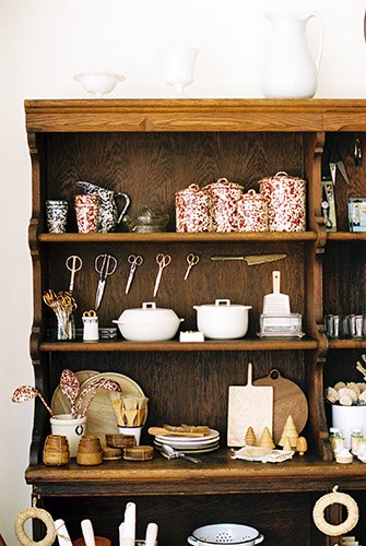 Wooden shelving unit displaying curated homeware, ceramics, kitchen utensils and decorative objects.