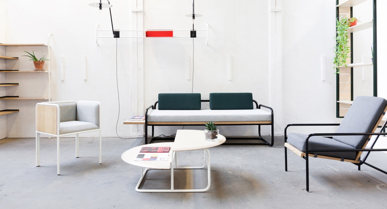 Modern sofa with tubular steel frame and oak-veneered panels in a minimalist interior setting.
