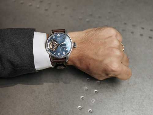 IWC Big Pilot's Watch with blue dial on wrist of person wearing dark suit and white shirt cuff.