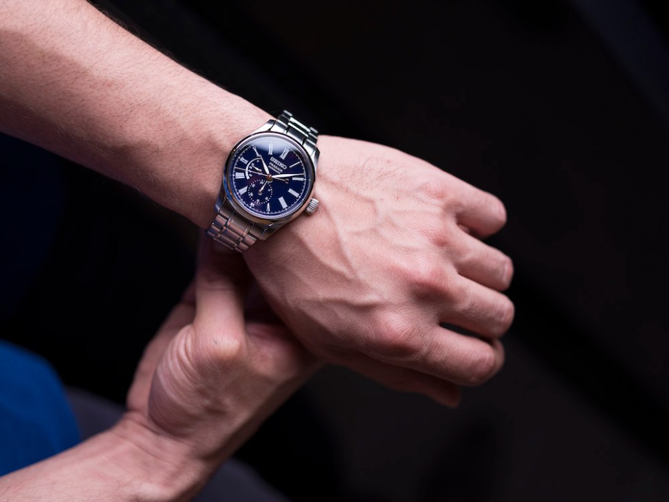 Seiko Presage watch with blue-enamel dial and steel bracelet worn on a wrist.