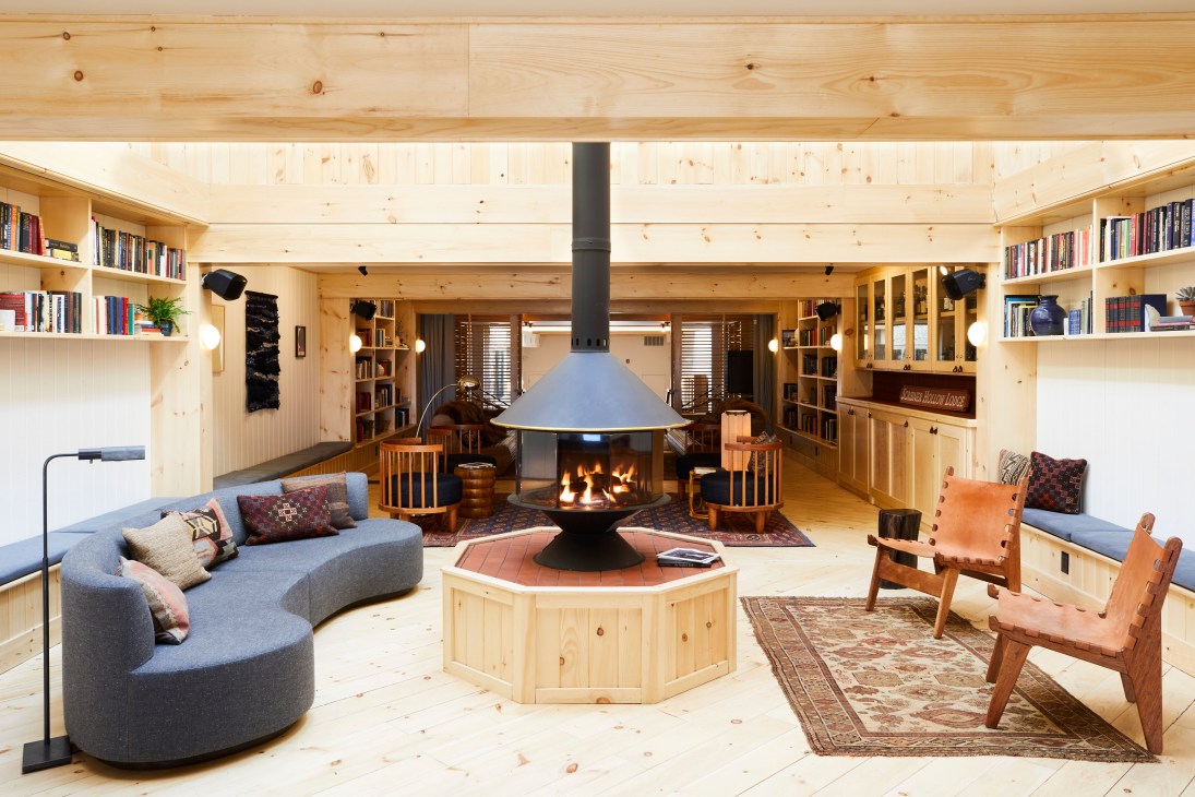 Library interior at Scribner's Catskill Lodge featuring wooden shelving, fireplace, and comfortable seating.