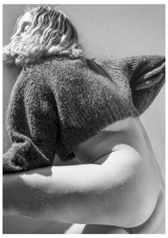 Black and white portrait photograph of a woman from behind wearing a textured sweater.