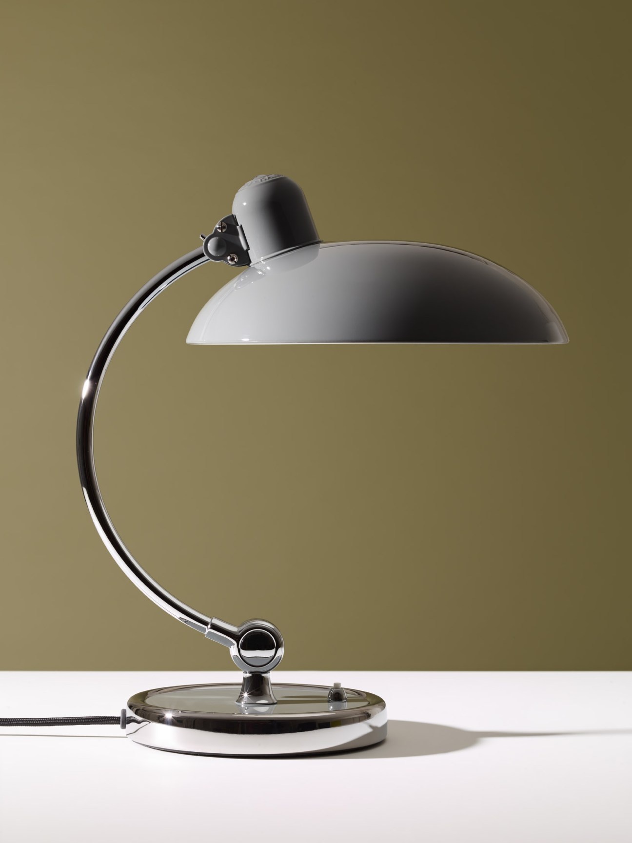 Kaiser Idell table lamp with curved black arm and white dome shade on circular base