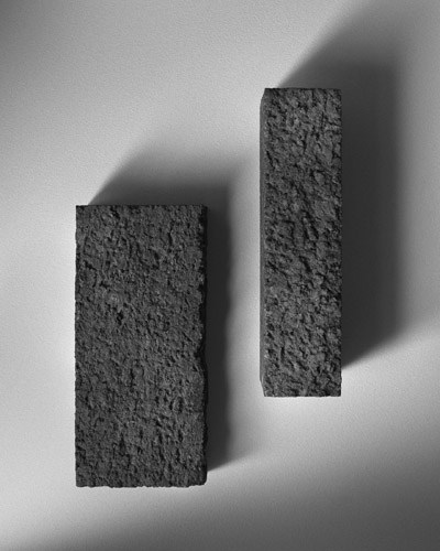 Two compressed cork bricks with textured surfaces casting shadows on white background.