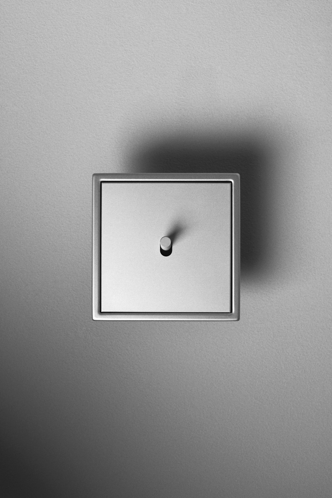 Jung LS 1912 rocker light switch in aluminium with refined design on white wall.