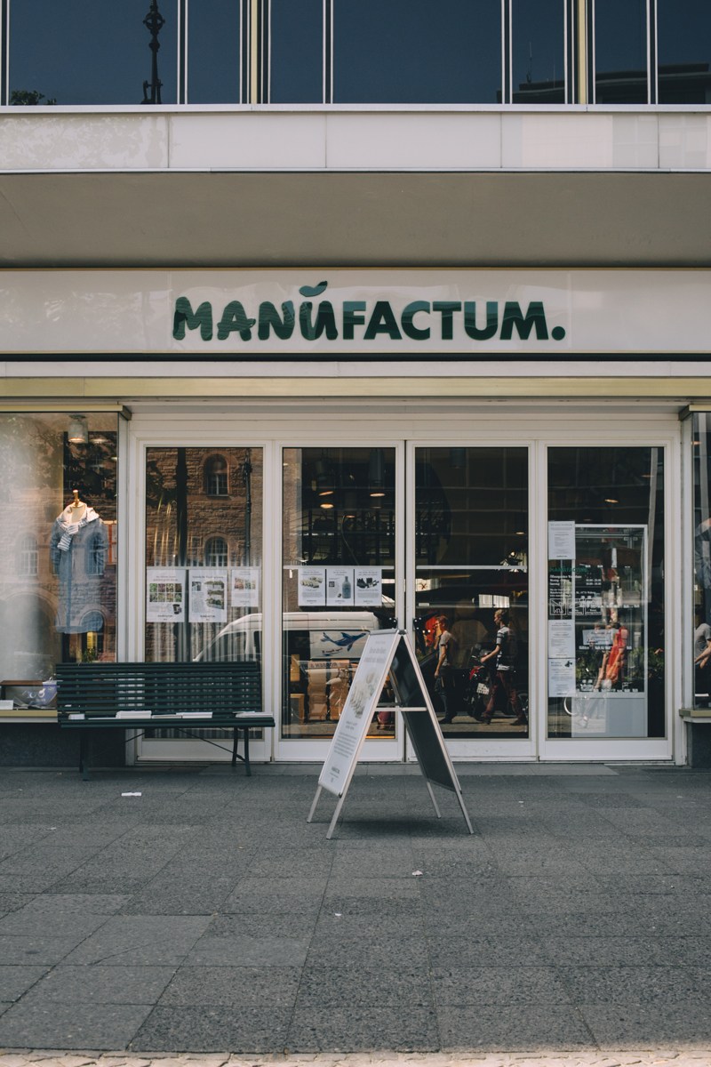 Manufactum storefront in Berlin with green signage and large windows displaying products.