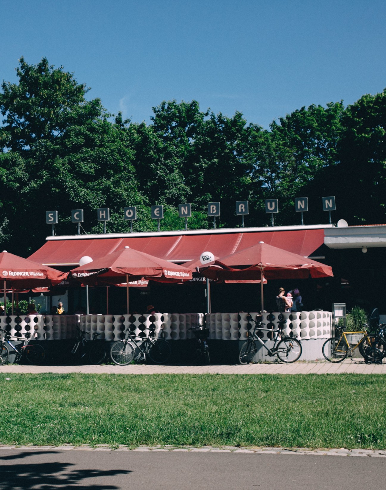 Schoenbrunn restaurant pavilion with red umbrellas and outdoor seating in Volkspark Friedrichshain