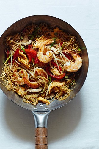 Singapore noodles with prawns, vegetables and bean sprouts being stir-fried in a wok