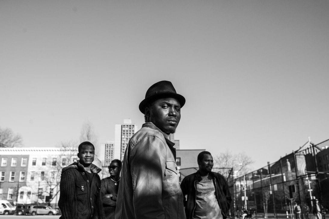 Black and white photograph of Songhoy Blues band members posing outdoors in urban setting.