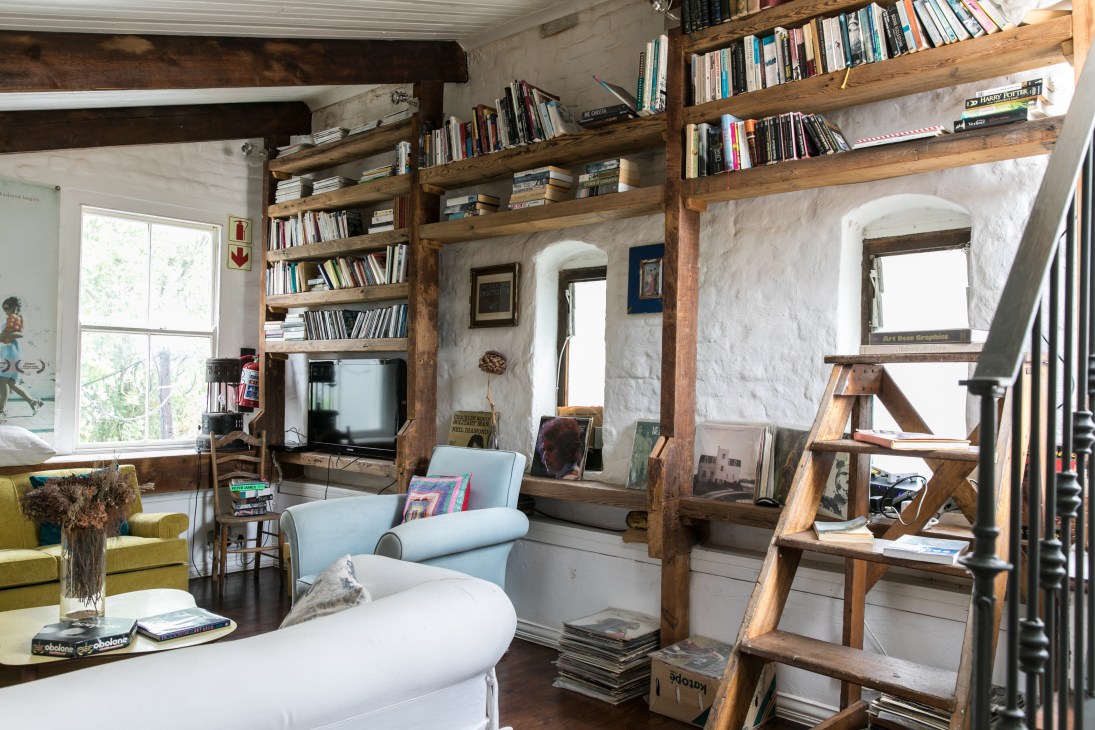 Interior of La Grenadine French pension with wooden beams, white walls, bookshelves, and modern furniture.