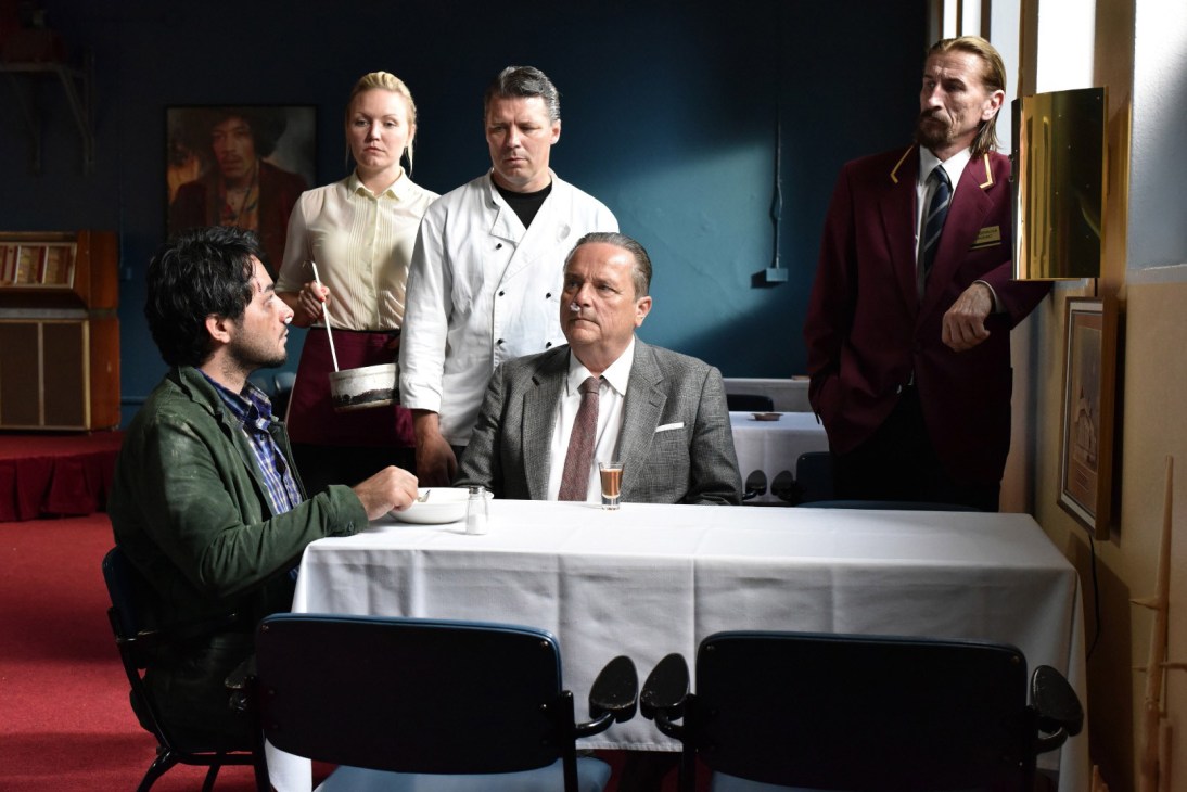 Scene from The Other Side of Hope film showing a man at a table with hotel staff standing nearby.