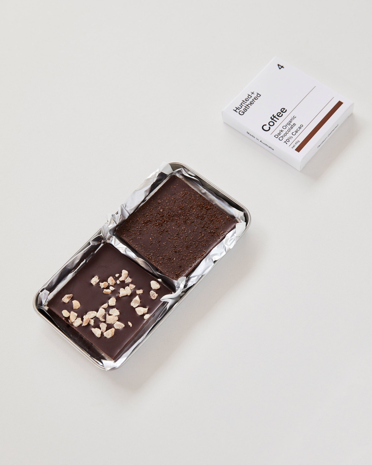 Hunted and Gathered chocolate bars and packaging displayed with native flowers and pastries in Melbourne café-retail space.