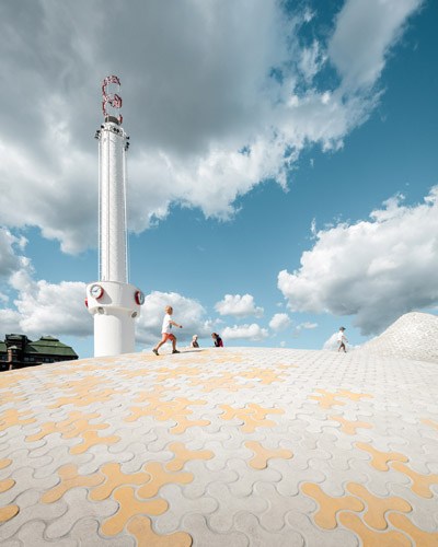 Amos Rex museum exterior with white tower and patterned ground on sunny day in Helsinki.